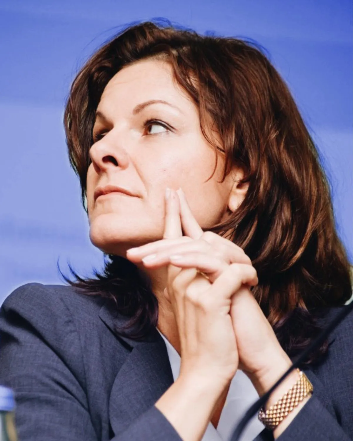 An executive listening in a meeting, hands clasped