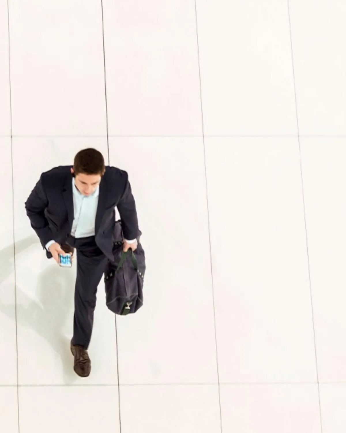A man in a suit crossing a bright tiled floor, seen from above